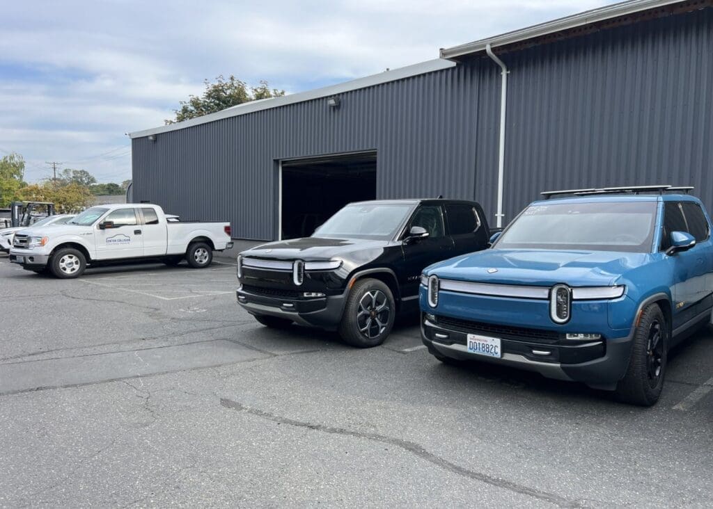 Two Rivian vehicles parked outside garage