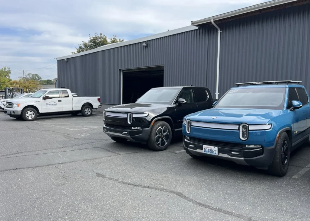 Rivian electric vehicles parked outside Center Collision auto body repair shop.